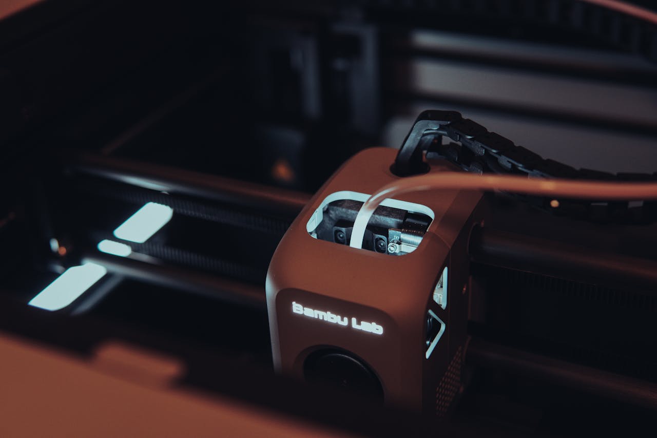 Welkom Detailed view of a 3D printer mechanism in a dark setting, highlighting technology.