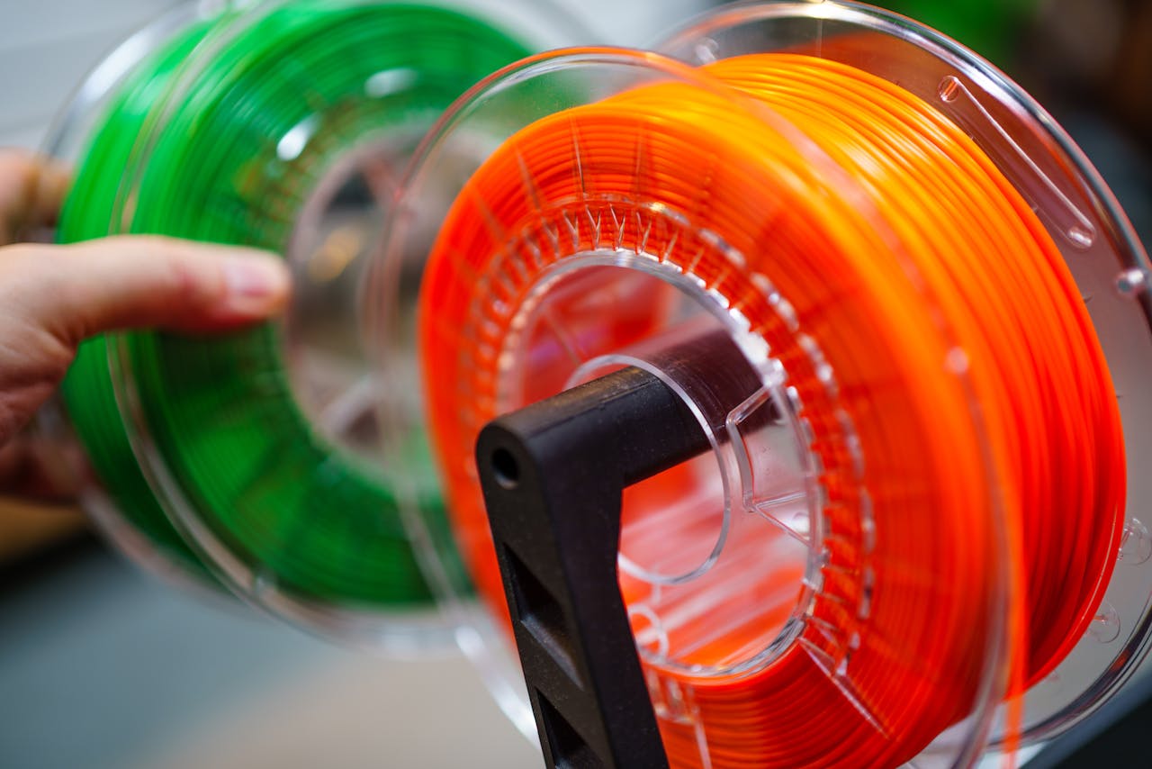 Welkom Vibrant orange and green 3D printer filament spools for innovative manufacturing uses.